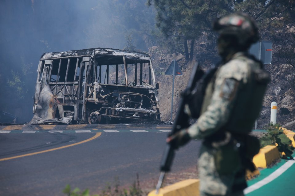 Un soldat stă de pază lângă un vehicul carbonizat după ce acesta a fost incendiat, în Cointzio, statul Michoacán, Mexic.